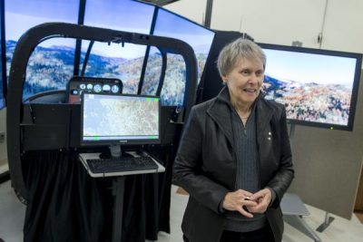 Roberta Bondar standing in front of a flight simulator in Carleton's ACELab