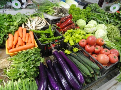 A colourful assortment of vegetables lays arrayed on a market stall table.