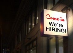 A sign above a business reads "Come in, we're hiring".