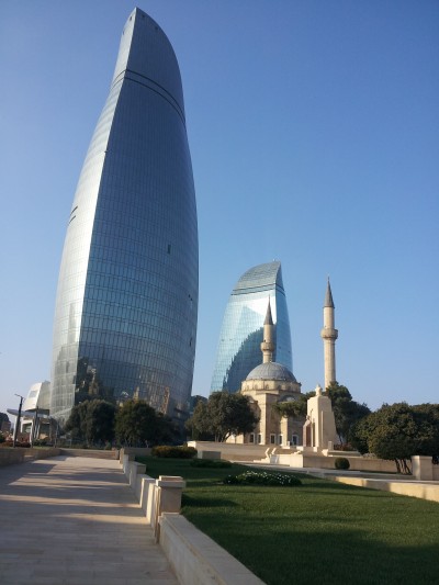 The Shahidlar Mosque is eclipsed by the Baku Flame Towers in Baku, Azerbaijan