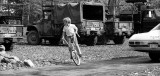 child cycling in front of armoured vehicles