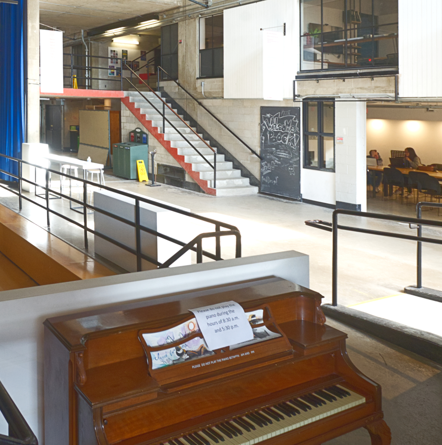 A piano sits in the foreground of an open space in Carleton's School of Architecture.