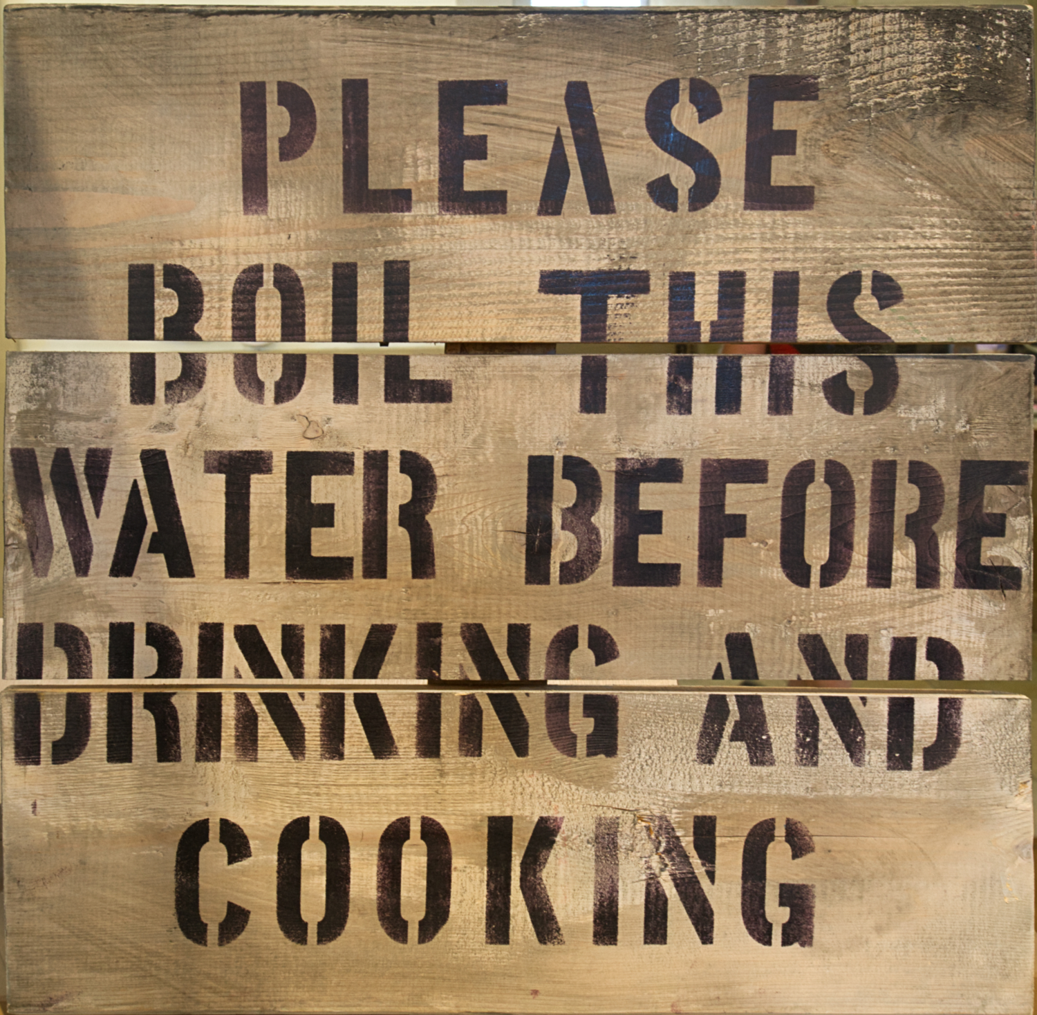 Wooden sign warning residents to boil water before consumption.