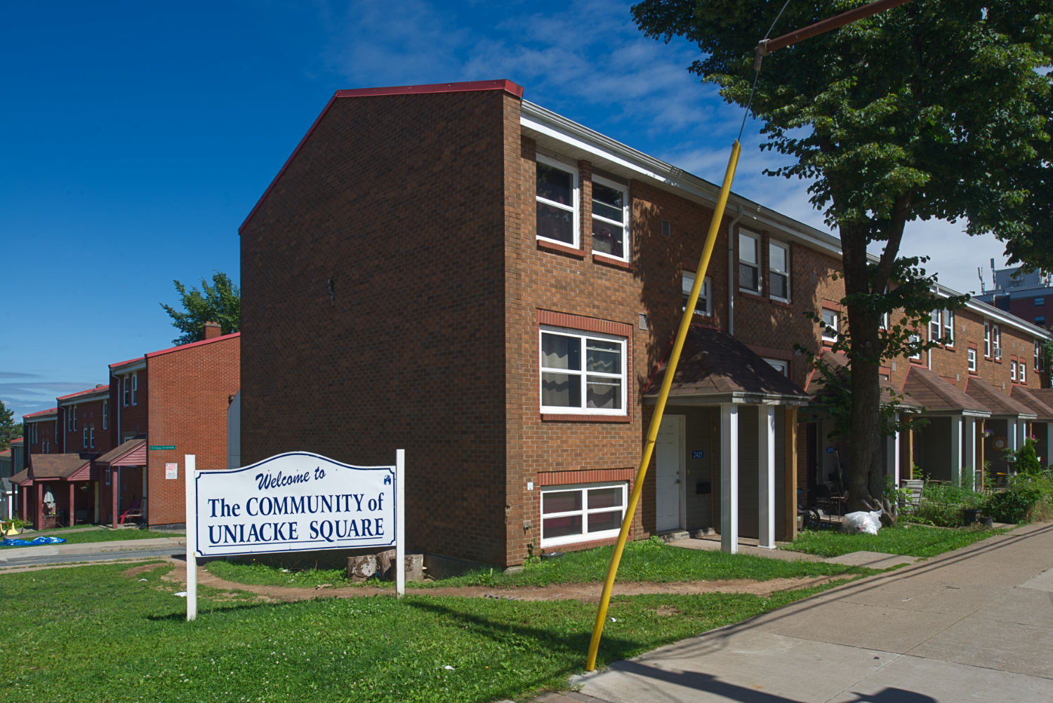 Brick row houses, with a sign welcoming people to the 'Community of Uniacke Square'.