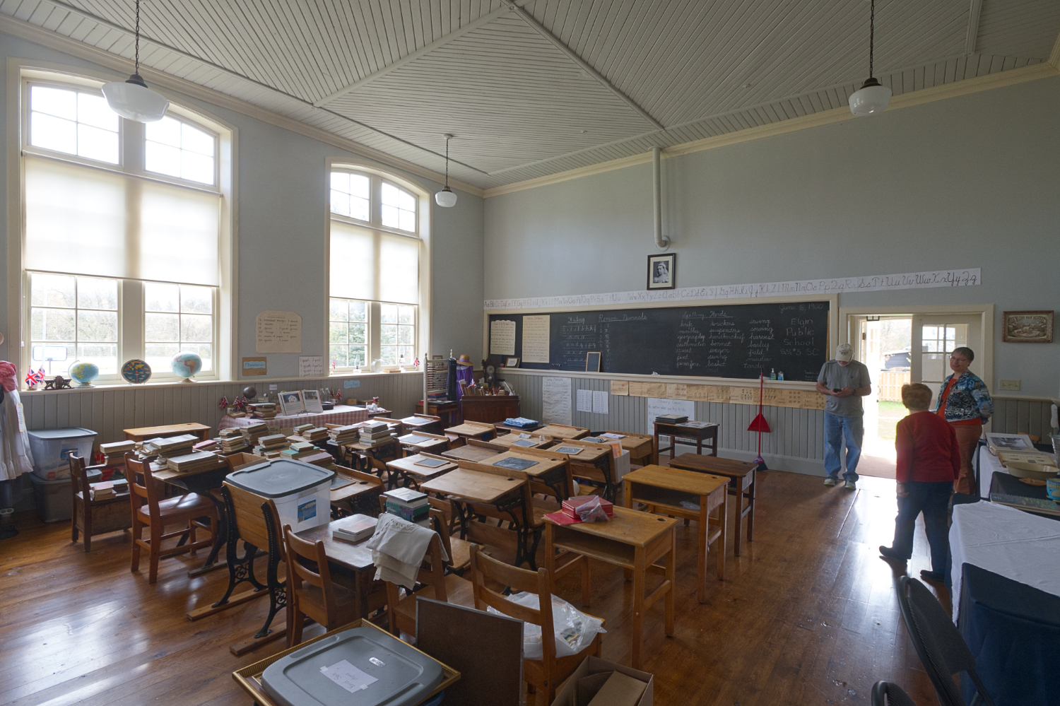 An old classroom full of desks, with big, bright windows.