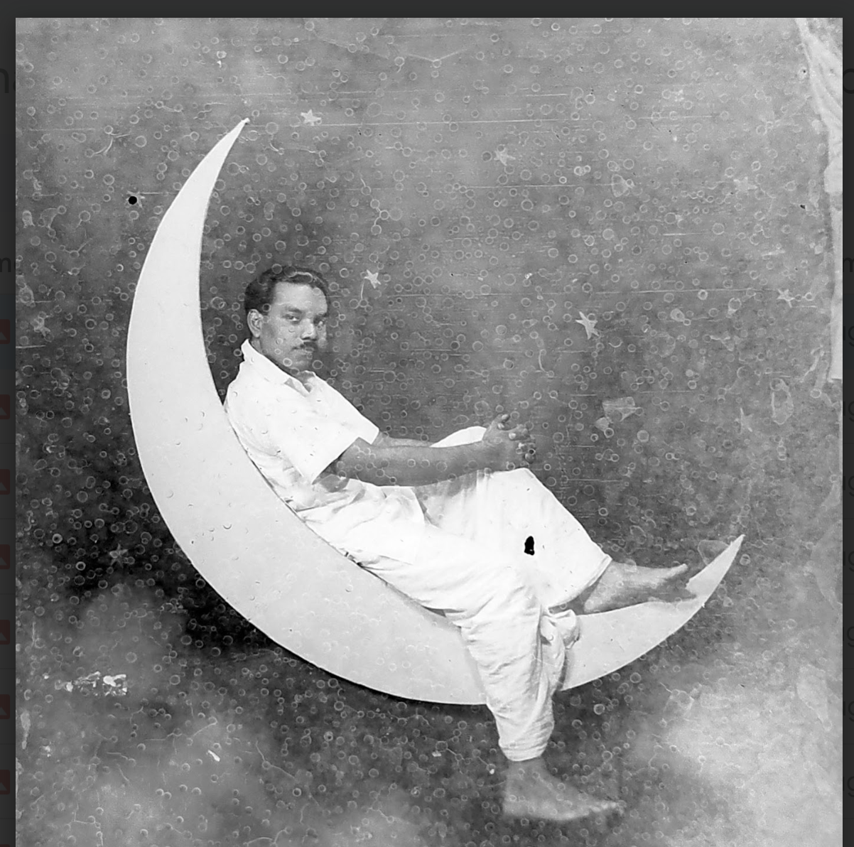 Black and white photograph of a man reclining in a crescent moon, from the Kovilpatti exhibition