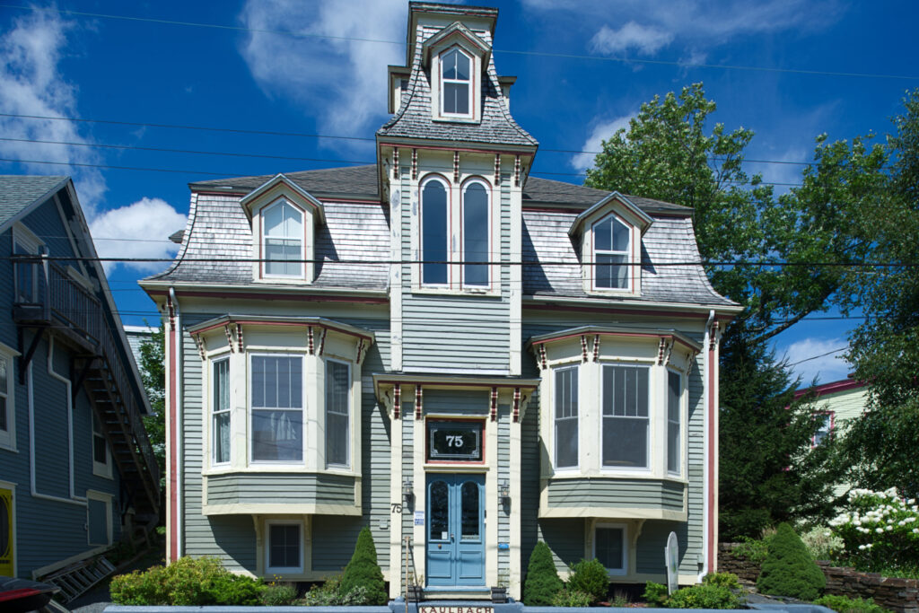 An elaborate two-story wooden house with a tower extending above the central doorway.