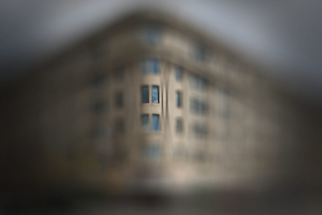 A barely discernible window sits near the centre of an image that becomes more blurry and darker as the eye travels from the centre. The outline of a building is suggested, but nothing is seen clearly.