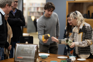 Image of several people viewing a selection of design objects on a table.