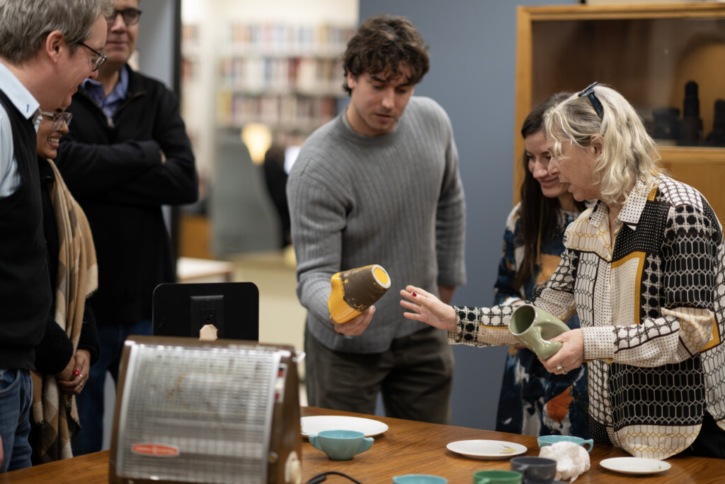 Image of several people viewing a selection of design objects on a table.