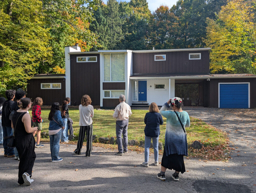 A group looks in admiration at a black and white Modernist house.