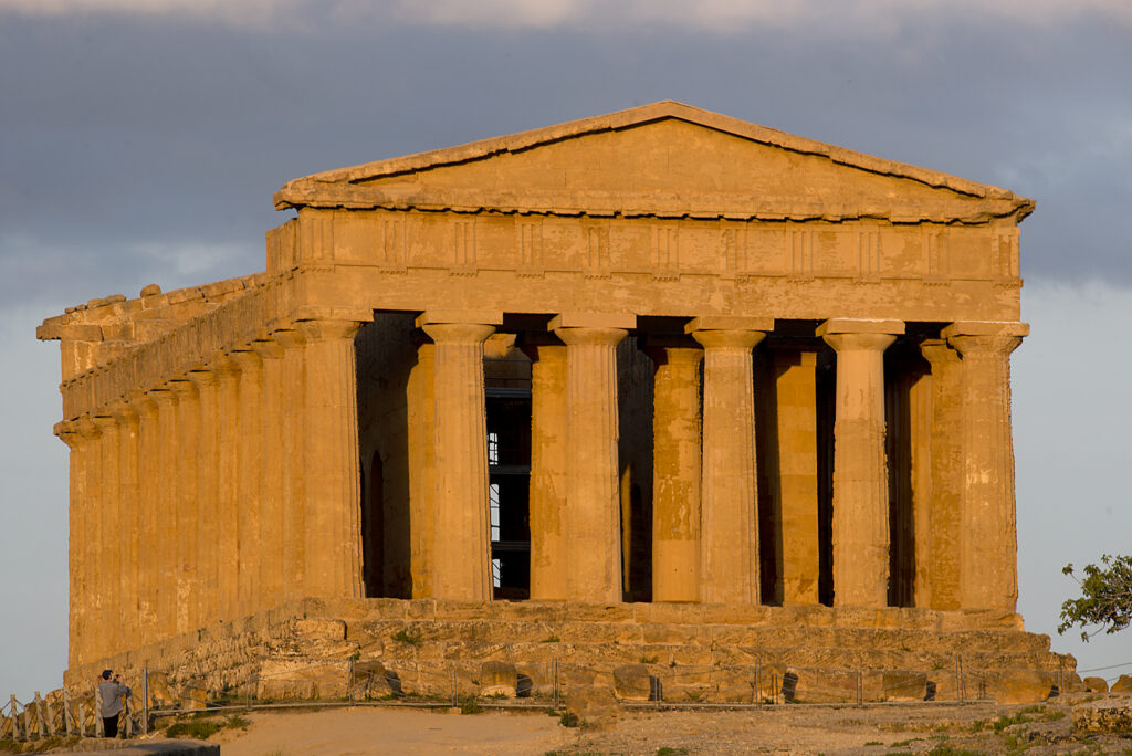 A well-preserved Ancient Greek temple is illuminated by the warm, setting sun.