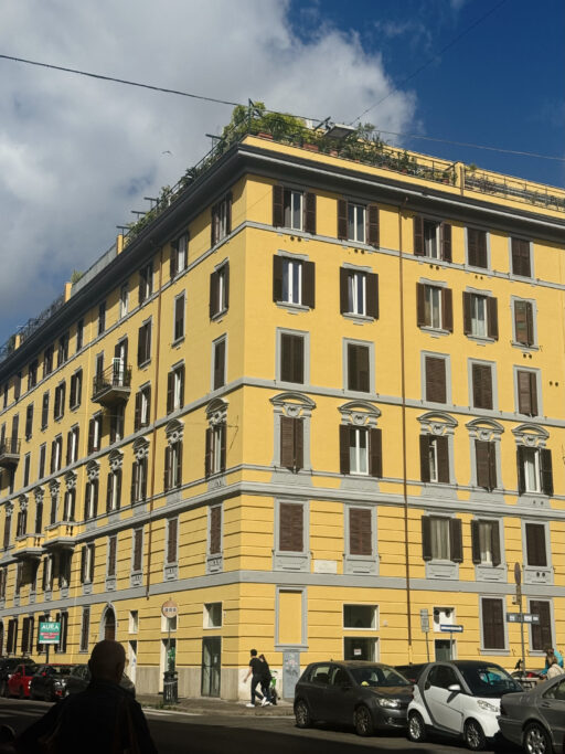 A bright yellow Classical building in an urban setting.