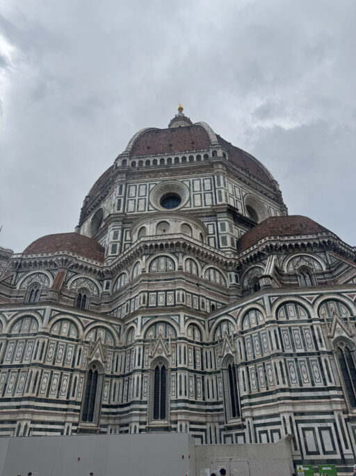 An ornate church exterior of patterned marble panels topped by a large dome.