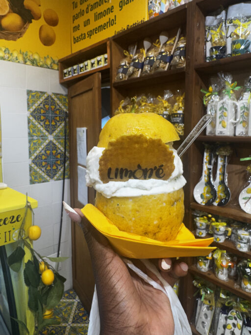 An outstretched hand holds a lemon gelato served in a lemon rind.