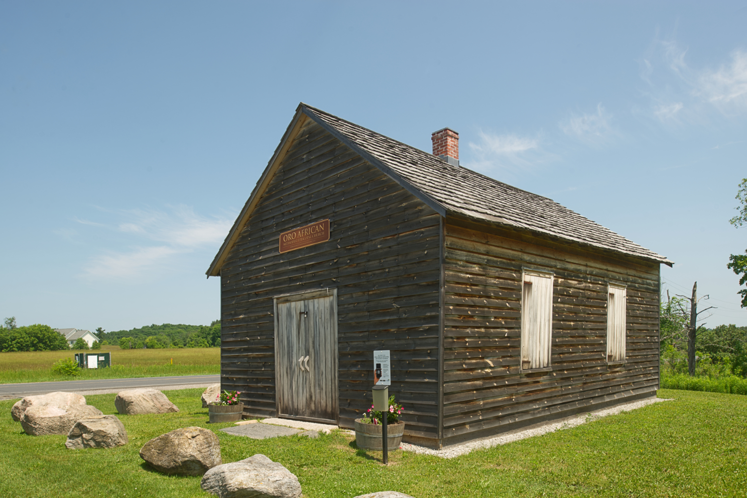 A log building sits in an open, grassy setting.