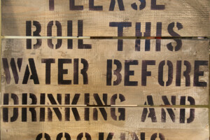Wooden sign warning residents to boil water before consumption.
