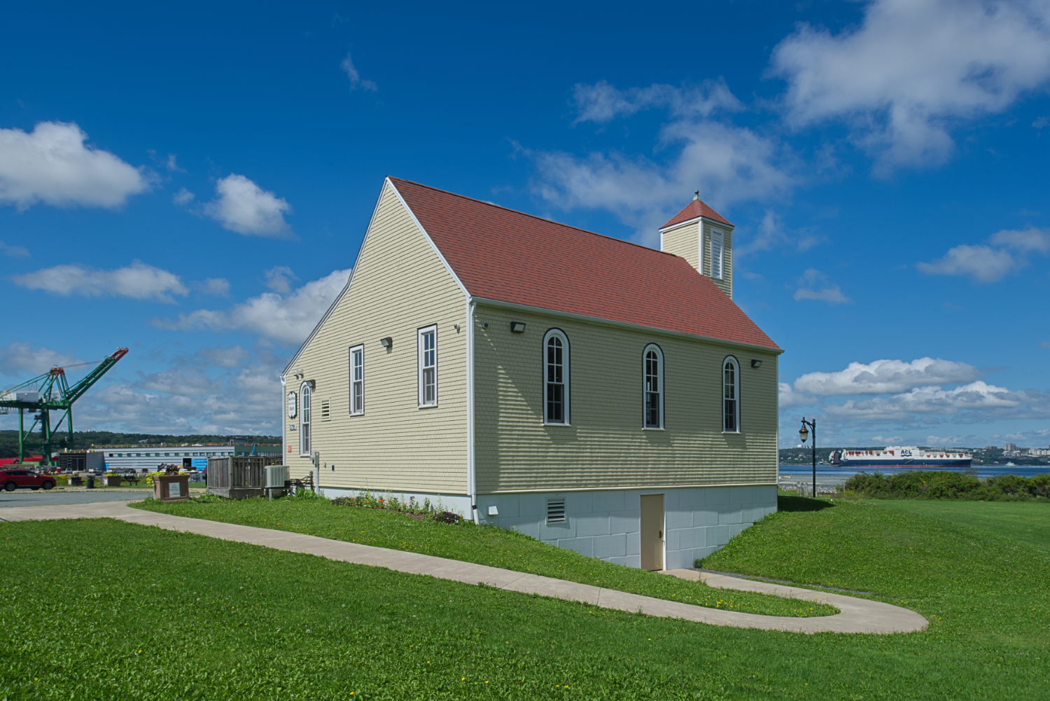 Yellow wooden church on a grassy clearing.