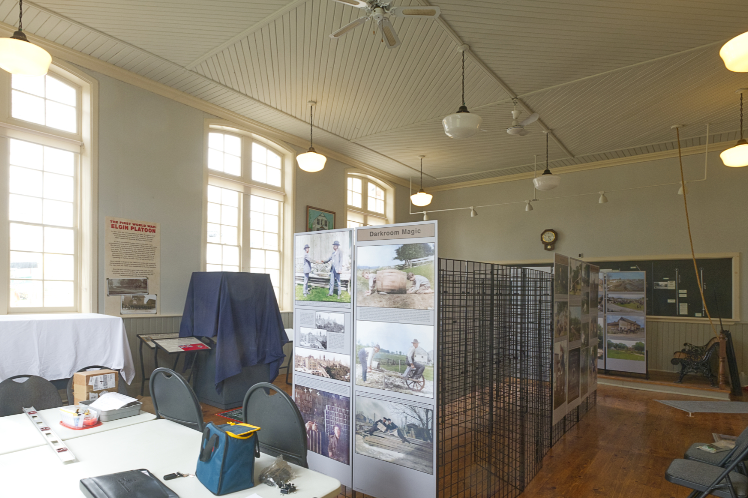 A large, bright room in an old building, with a partially installed photographic exhibition.