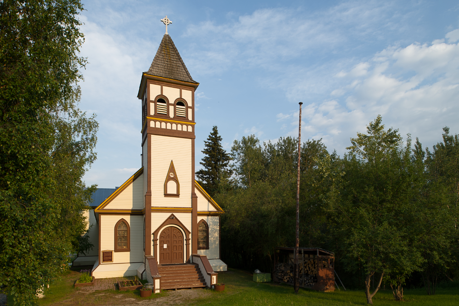 A wooden Gothic Revival church sits among trees.