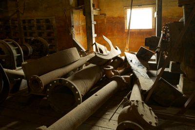 Unused, rusted industrial equipment sits piled up in an abandoned factory.