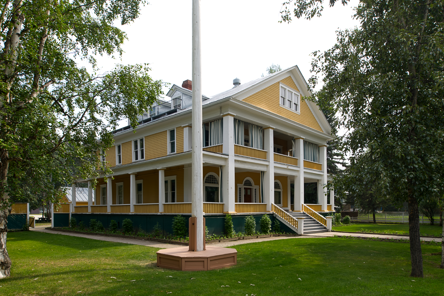 A stately wooden building, Classical in style, with a surrounding vernda.