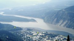 View from an elevated height of a town settlement in the foreground, with two converging rivers behind and steep hills in the background. The letters 'A' and 'B' are marked at two points near the rivers' confluence.