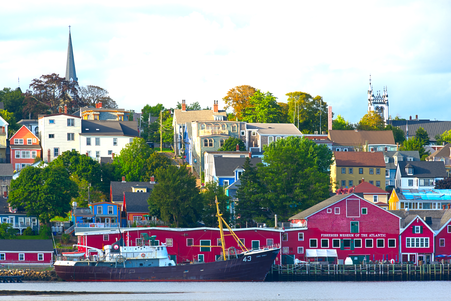 Colourful wooden vernacular architecture sits on the edge of a harbour.