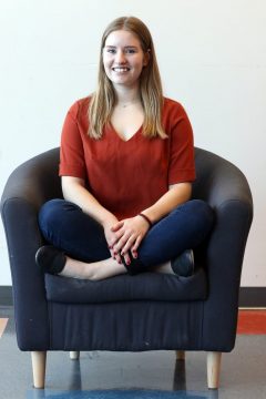 ACT to Employ student sitting on a chair in her workplace.