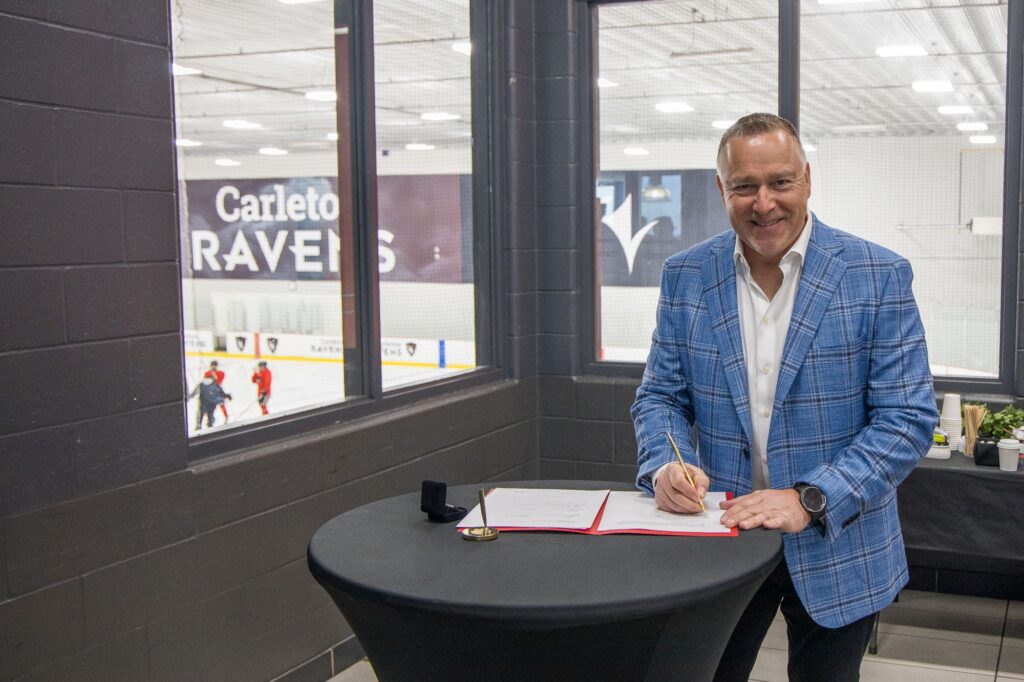 Mike Hapke signs at a raised black table