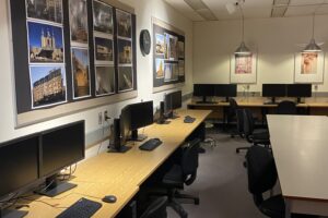 A photo of the student lounge showing tables along two walls with computer workstations on each table.