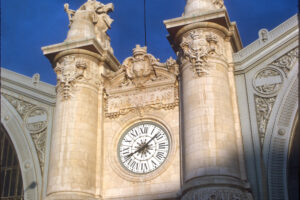 Image captures a french clock tower in sun and shade.