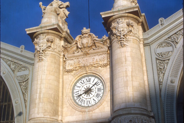 Image captures a french clock tower in sun and shade.