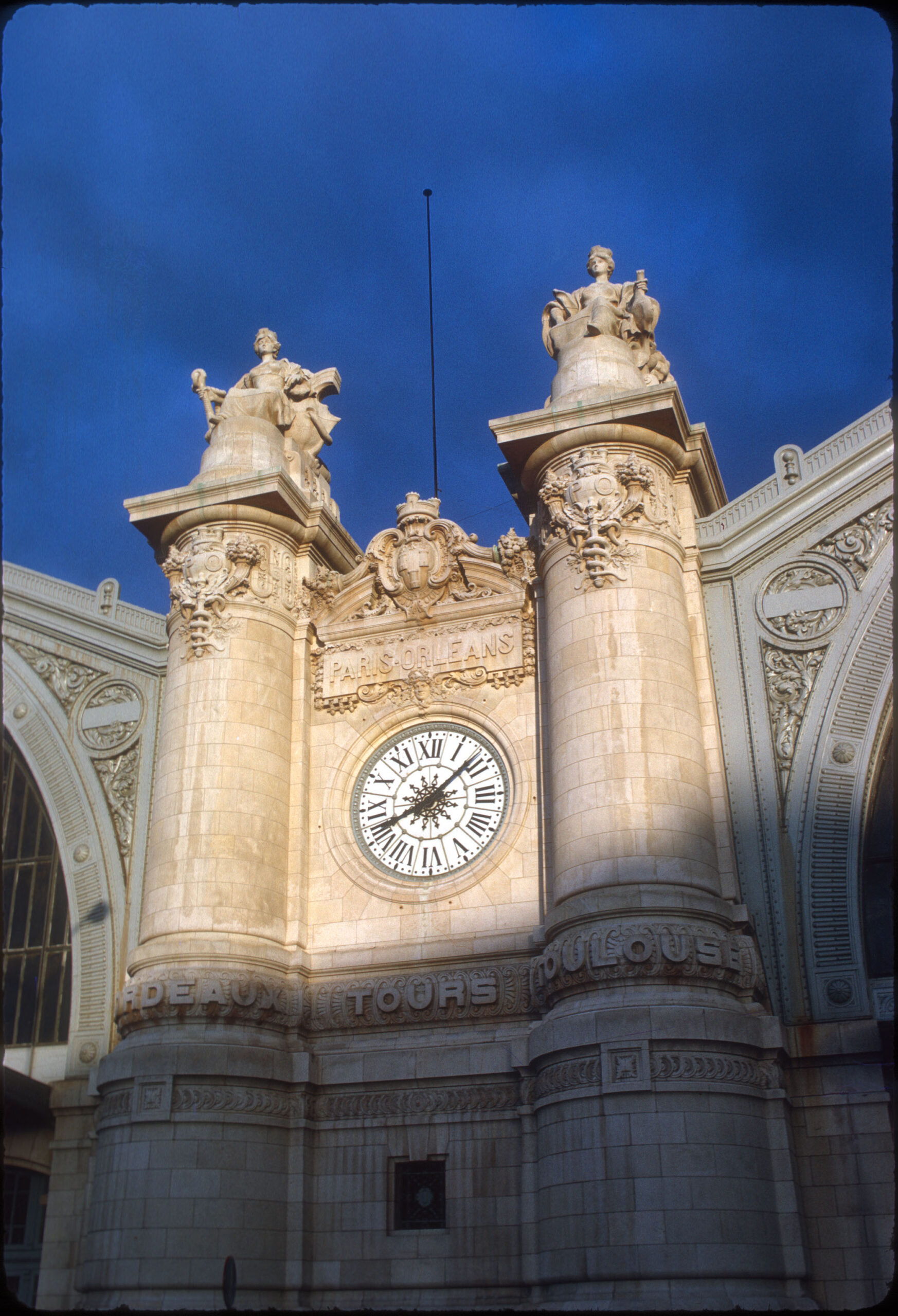 Image captures a french clock tower in sun and shade.