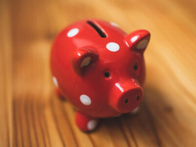 Image of a red, and white polka dotted piggy bank on a wooden table