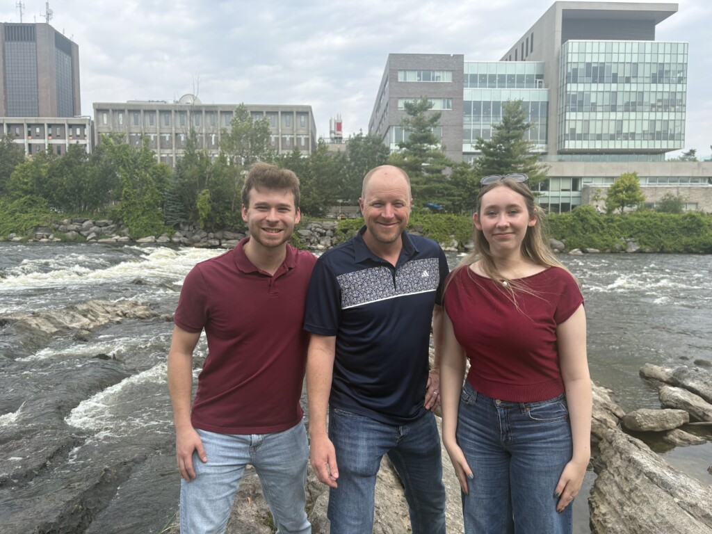 picture of researchers 2 students and one faculty member in front of Carleton University