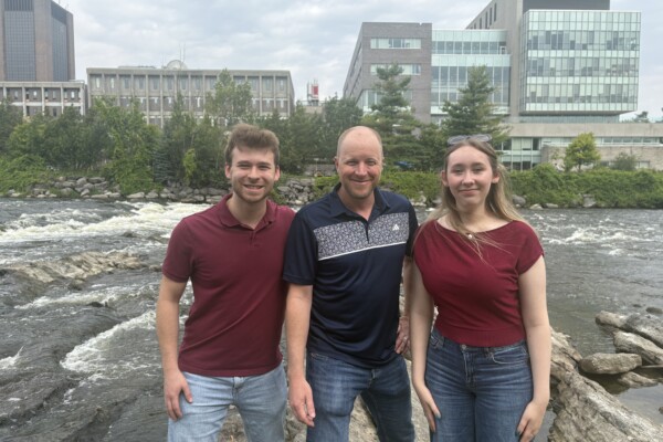 picture of researchers 2 students and one faculty member in front of Carleton University