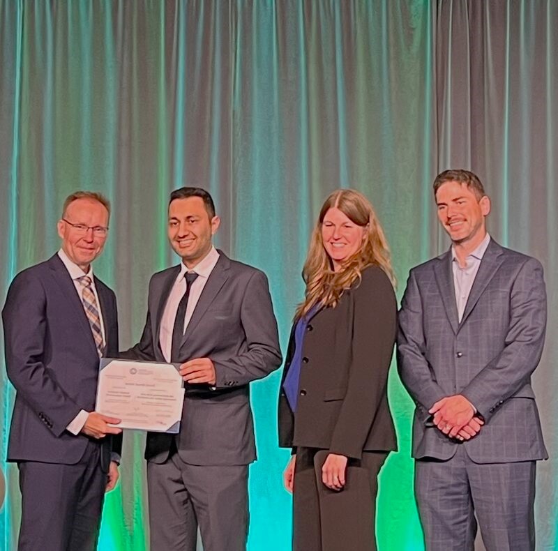 Armin Saeedi Javadi is pictured wearing a black and white suit on stage while receiving an award from CGS.