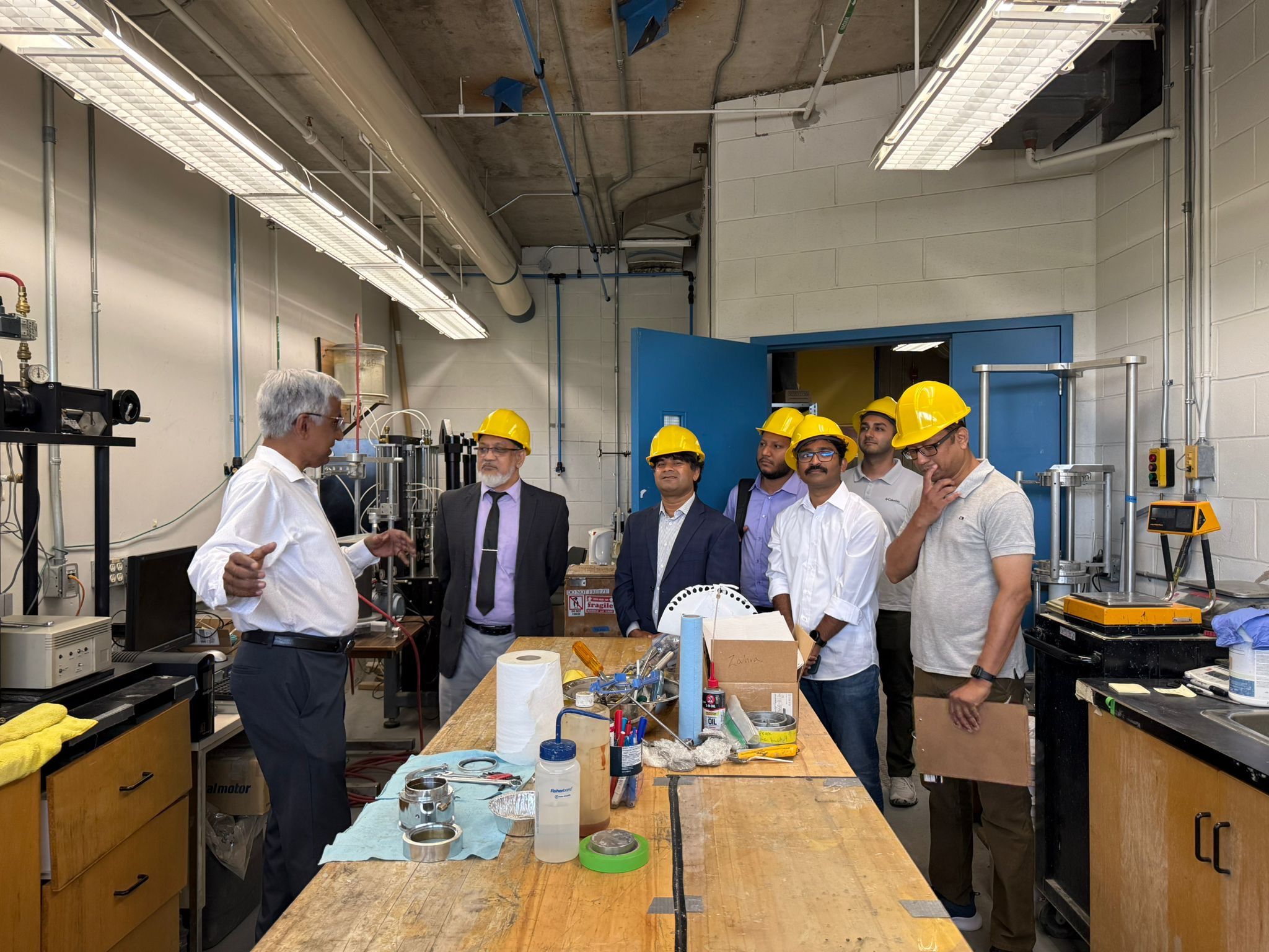 A group of faculty review a Geotechnical Lab with Prof. Siva Sivathayalan.