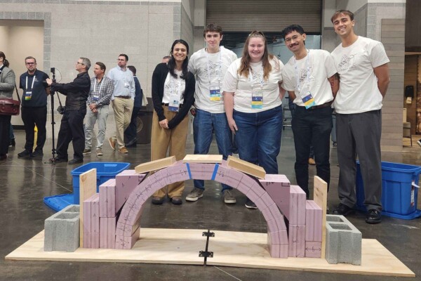 Students posing in front of a masonry arch