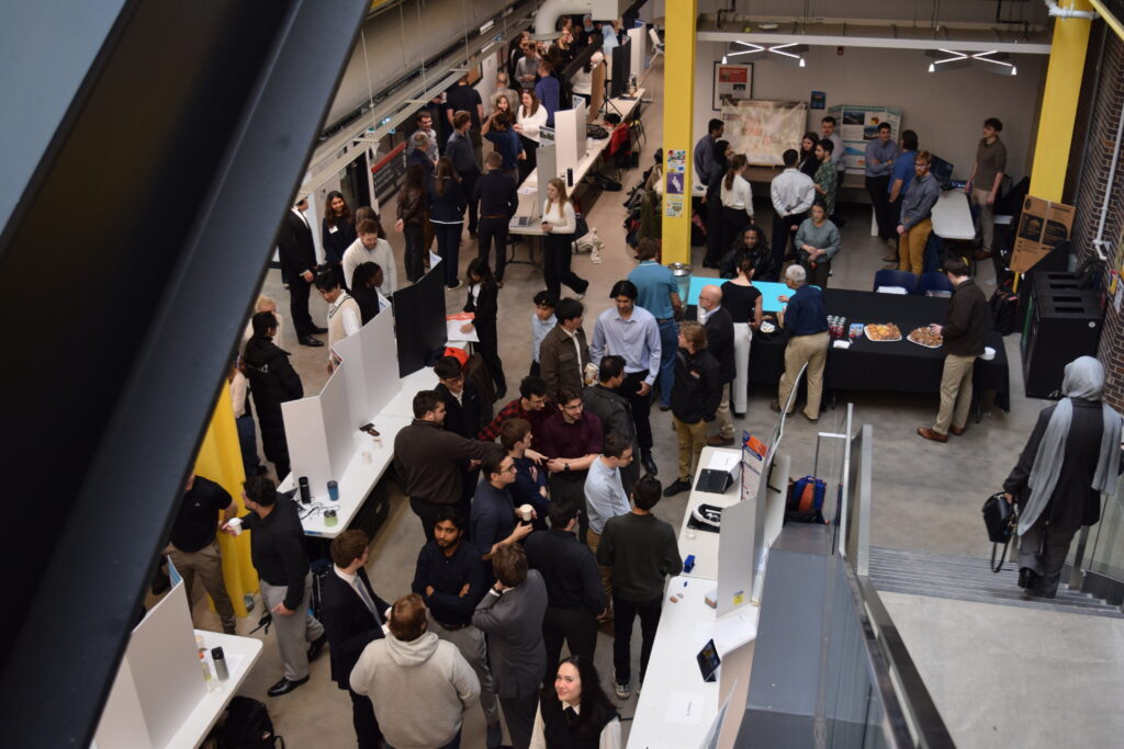 Image shows multiple capstone groups presenting their projects to students, professors and mentors in the Eng Design Centre