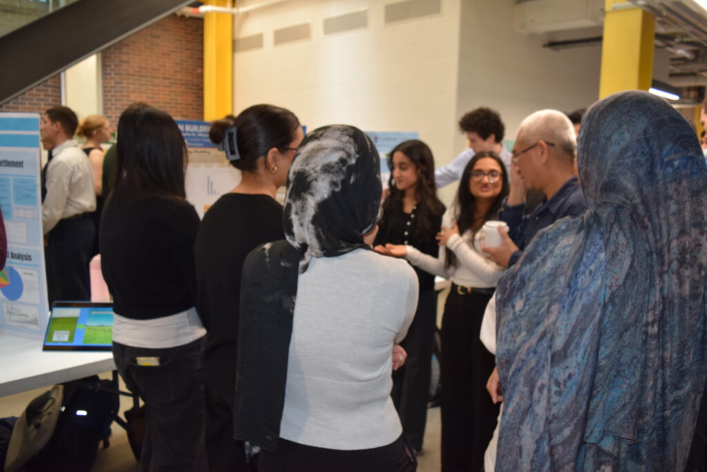 Image shows a group of undergraduate students presenting their capstone project to a professor