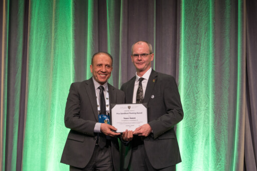Dr Yasser Hassan posing with his Sandford Fleming Award certificate next to a CSCE member 