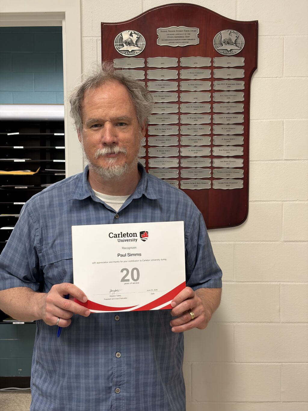 Professor Paul Simms posing with his certificate of 20 years of service at Carleton University