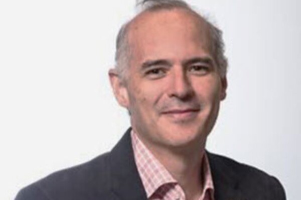 Photo of Mario Santana Quintero wearing a pink shirt and black blazer.