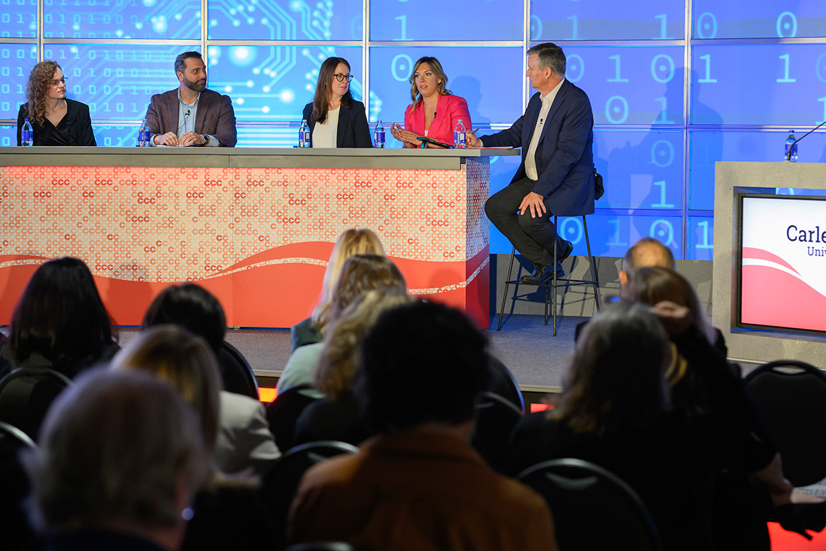 Five people sitting on a panel discussion during a conference to discuss AI and risk.