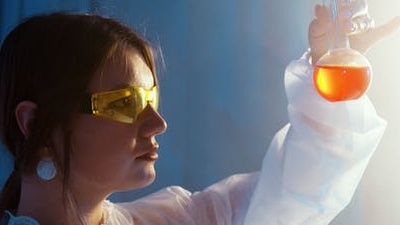Student looking at beaker with orange liquid 