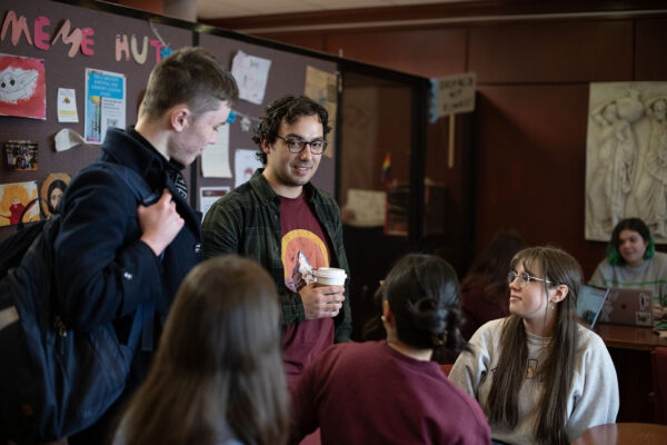Students chatting, one person holds a coffee cup
