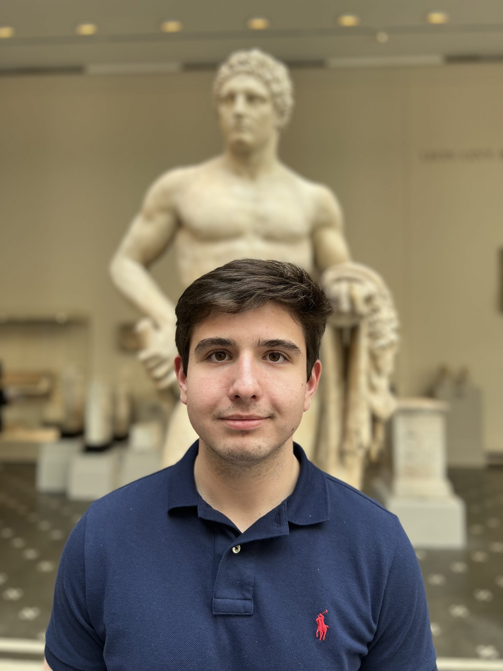 Photo of Christos in front of a statue