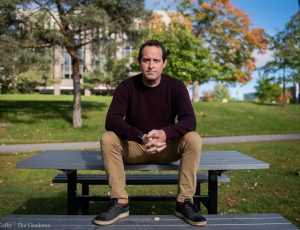 Dr. Shane Gero poses on a bench outside on campus.